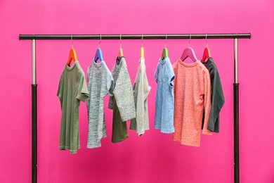 Rack with stylish child clothes on color background