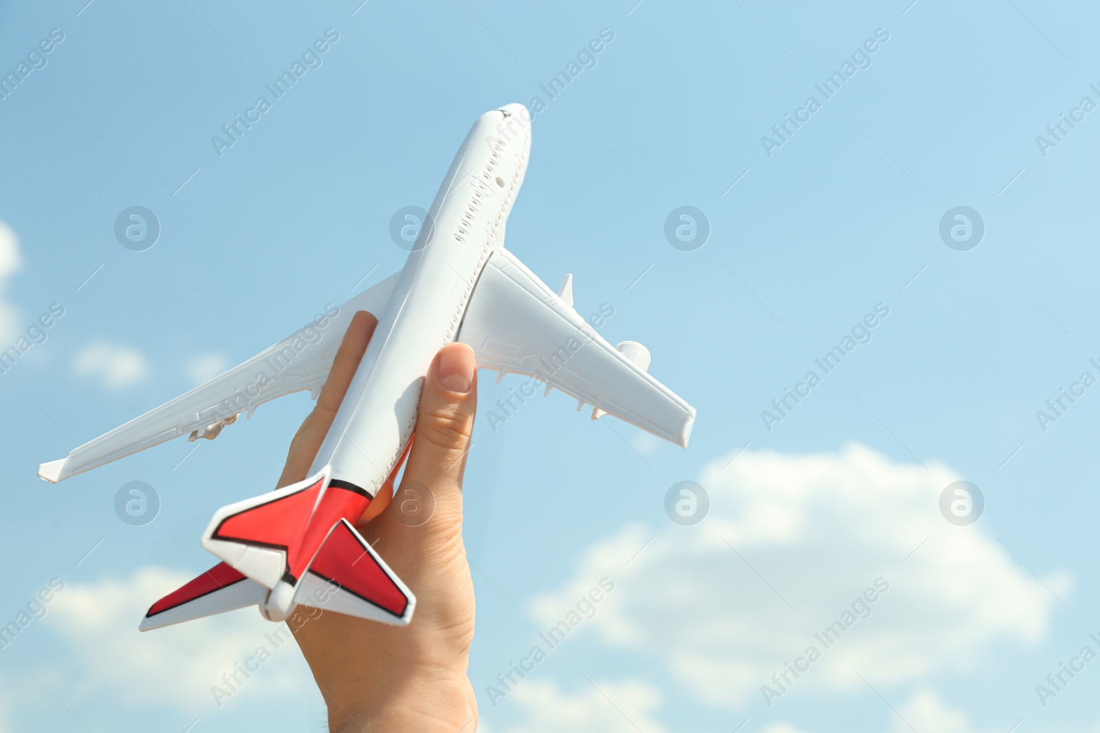 Photo of Woman holding toy airplane against blue sky, closeup