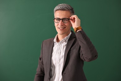 Photo of Portrait of teacher in glasses near chalkboard