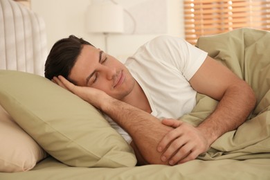 Photo of Man sleeping in bed with green linens at home