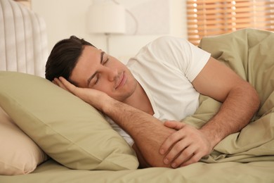 Man sleeping in bed with green linens at home