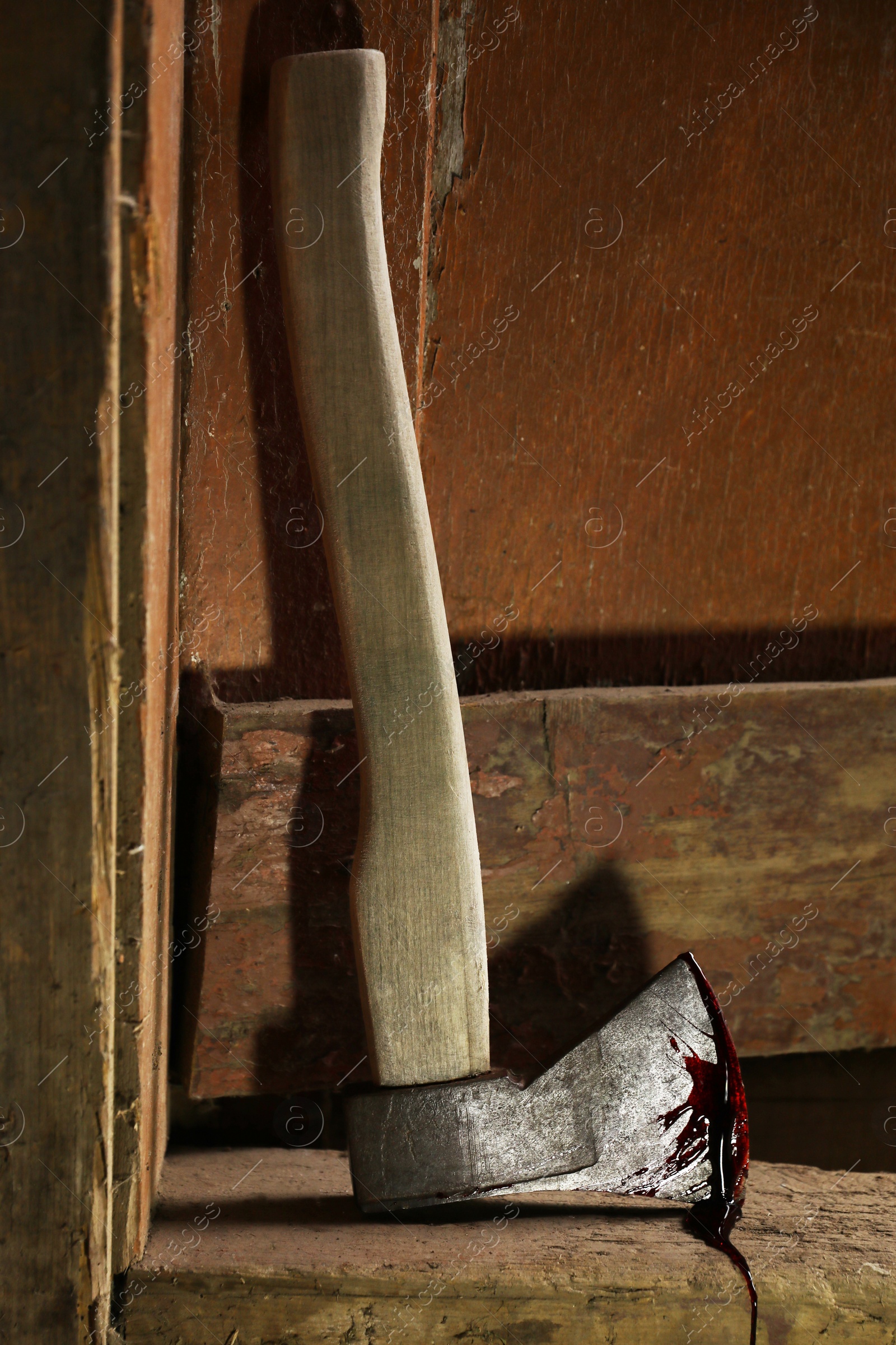 Photo of Axe with blood on wooden threshold indoors