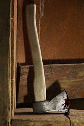 Axe with blood on wooden threshold indoors