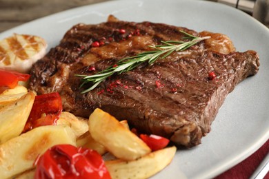 Photo of Delicious grilled beef steak and vegetables on plate, closeup