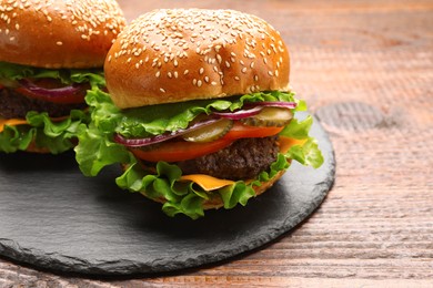 Tasty burgers with patties and vegetables on wooden table, closeup. Fast food