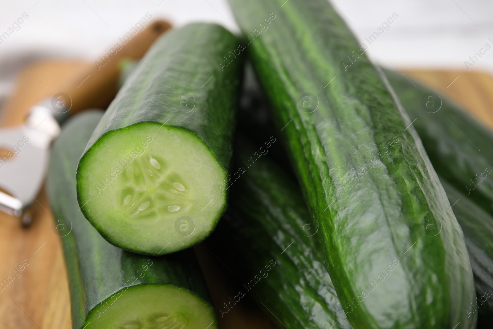 Photo of Many fresh cucumbers on wooden board, closeup