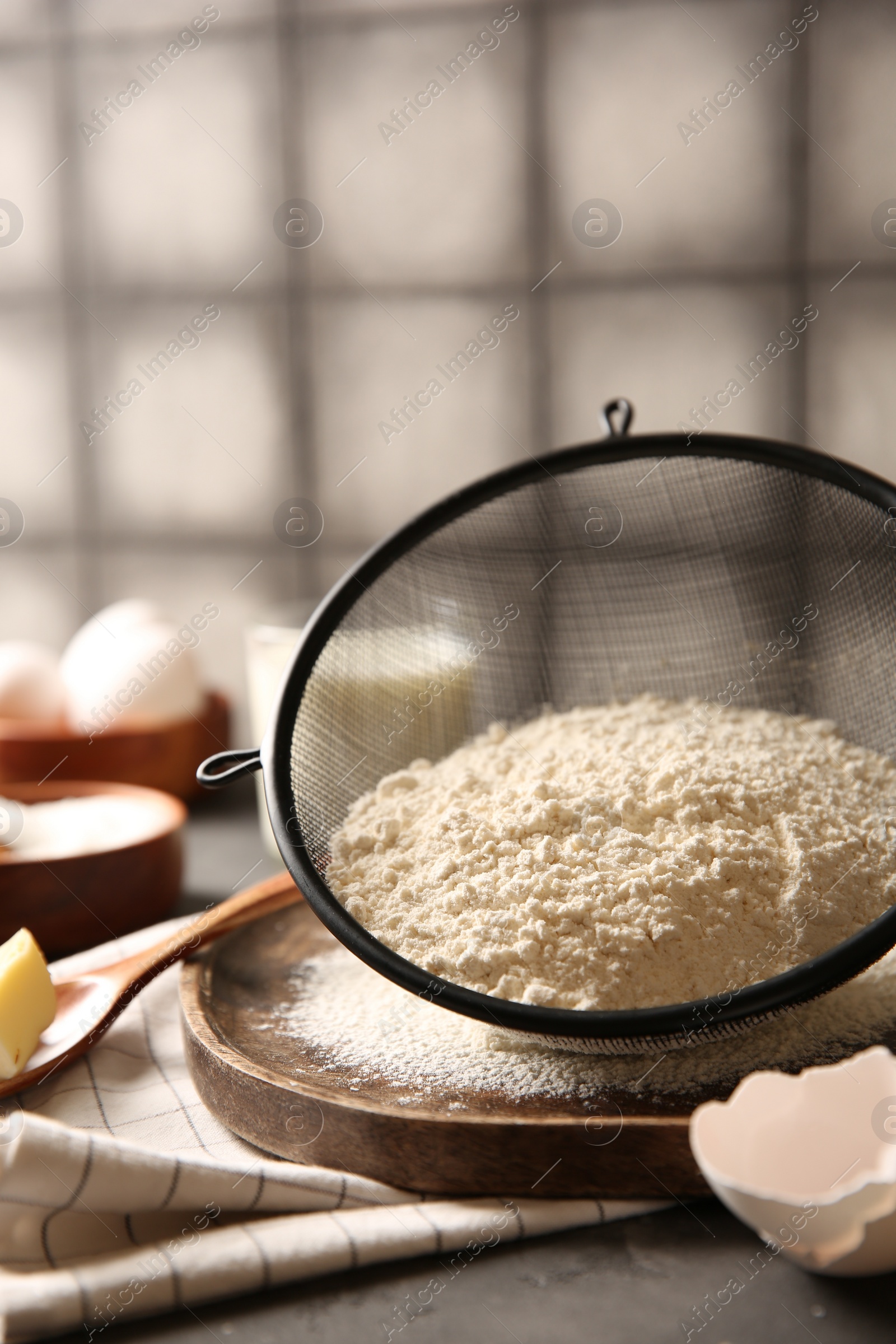 Photo of Making dough. Flour in sieve on grey table, closeup