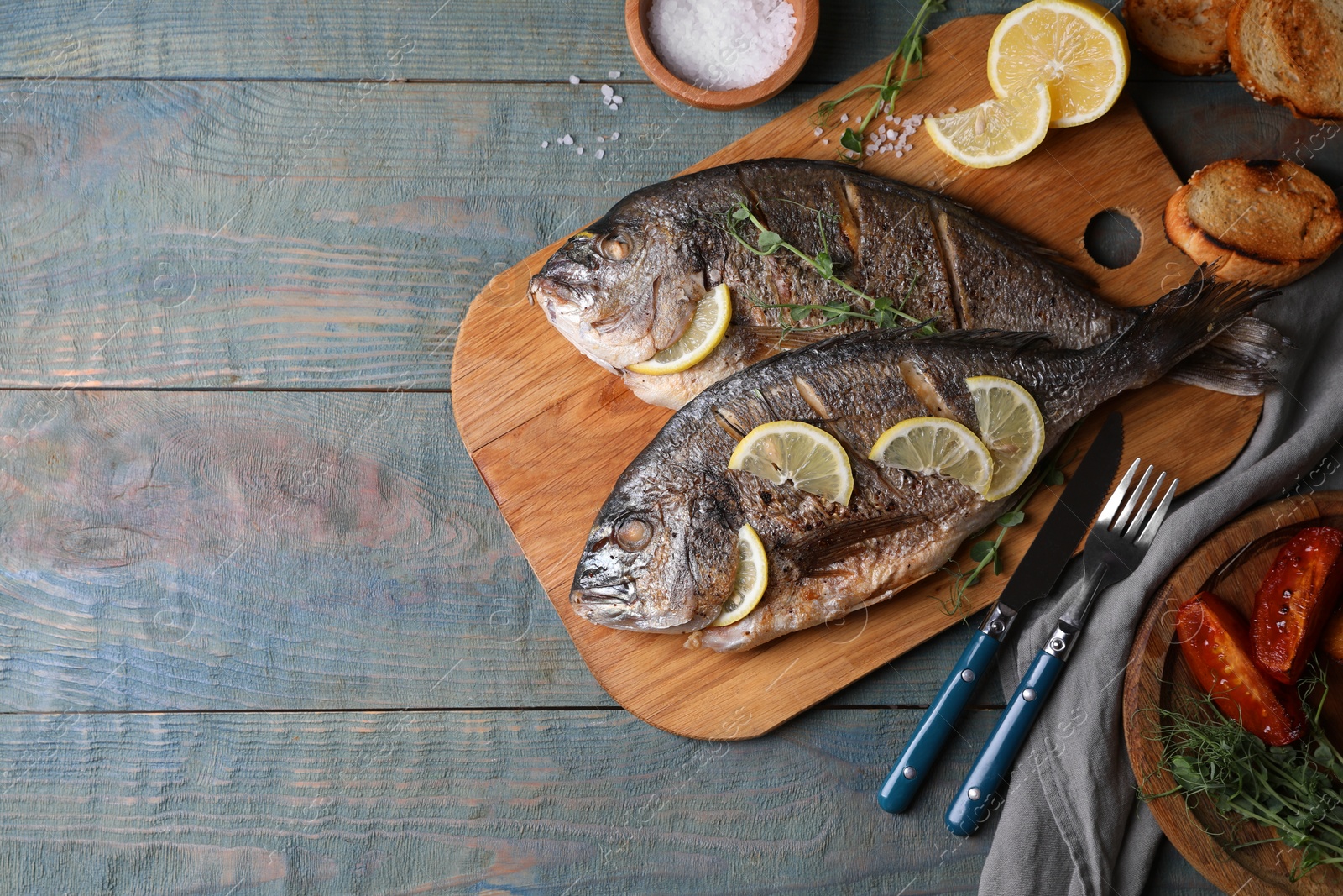 Photo of Delicious baked fish served on wooden rustic table, flat lay with space for text. Seafood