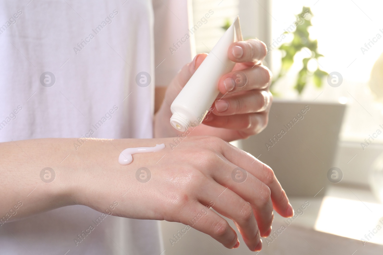 Photo of Woman applying hand cream at home, closeup