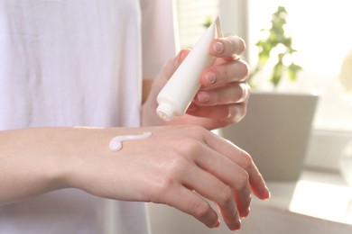 Woman applying hand cream at home, closeup