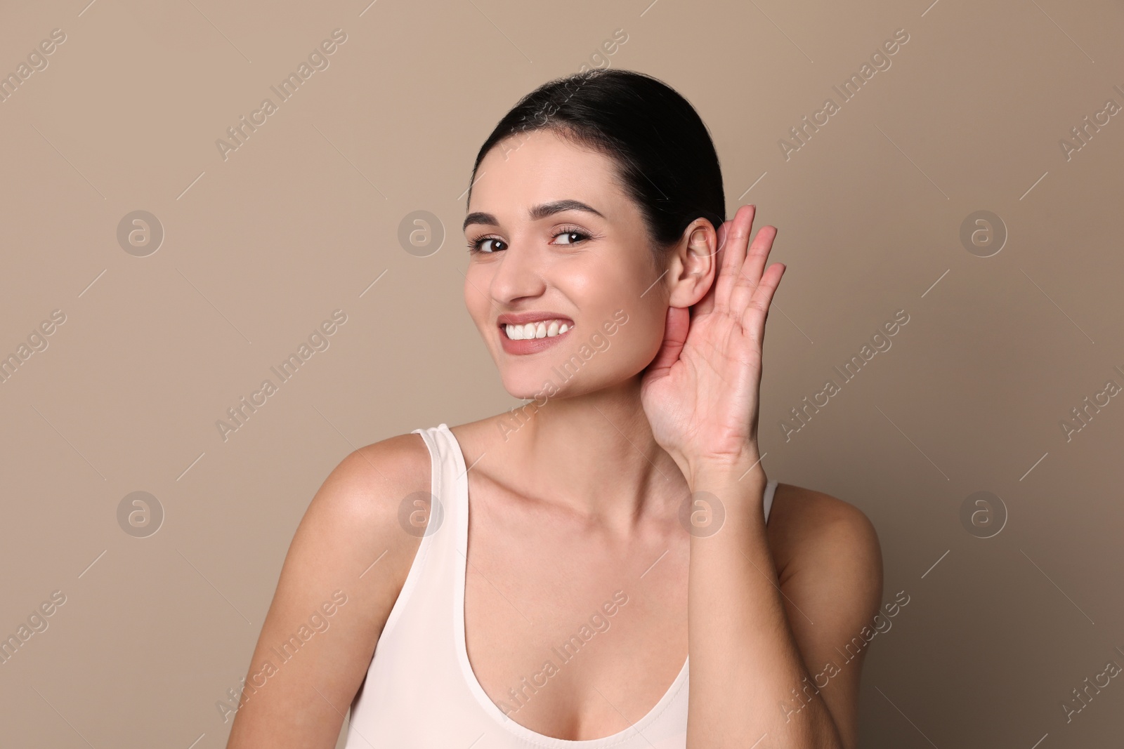 Photo of Young woman showing hand to ear gesture on grey background