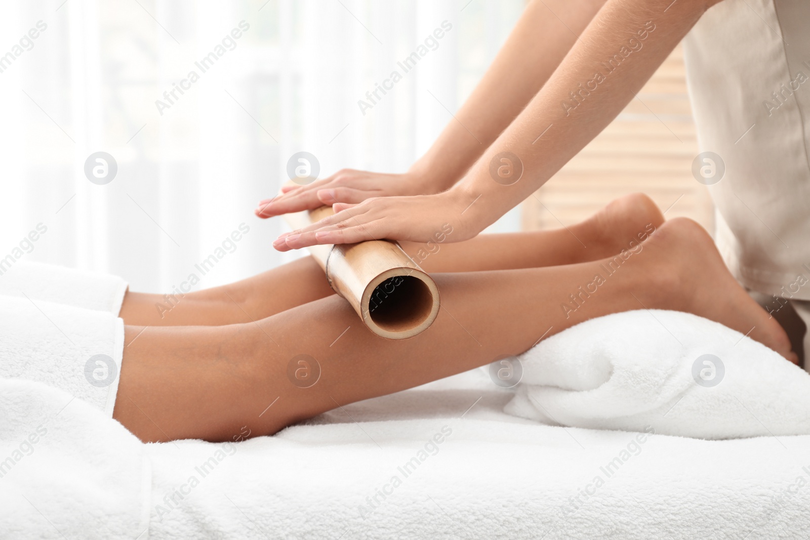 Photo of Woman having massage with bamboo stick in wellness center