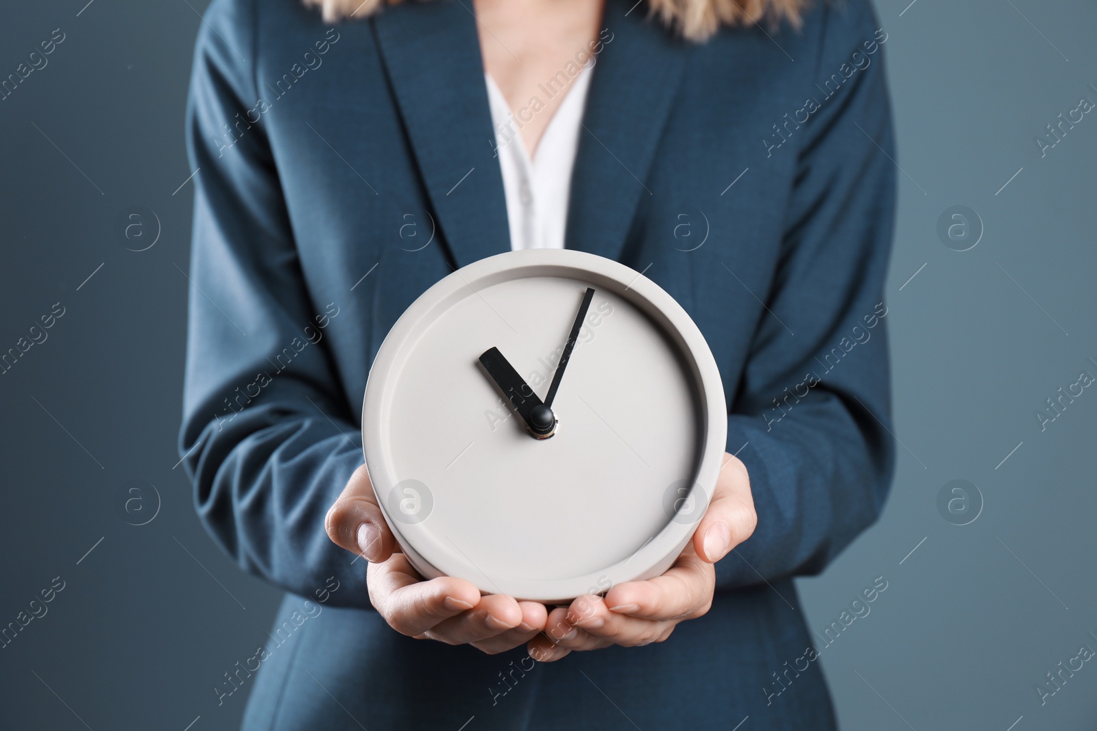 Photo of Young businesswoman holding clock on color background. Time management