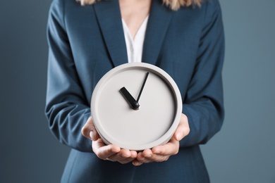 Photo of Young businesswoman holding clock on color background. Time management