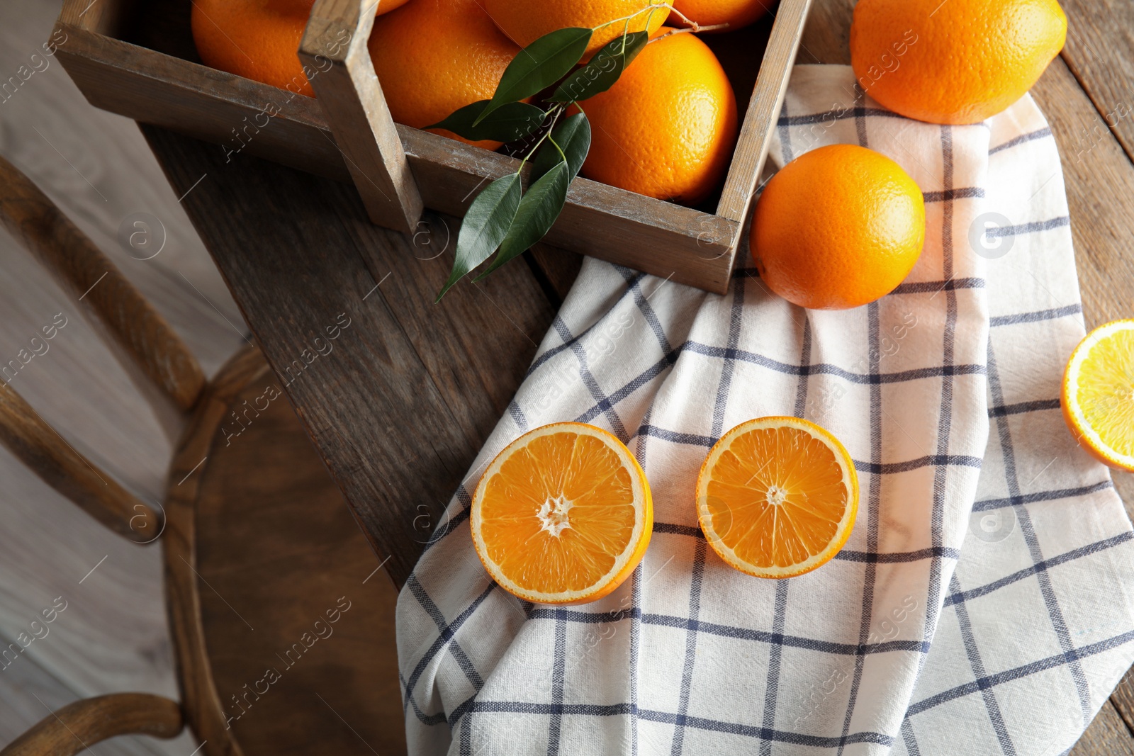 Photo of Fresh oranges with leaves and rustic box on wooden table, above view