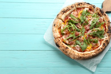 Tasty pizza with meat and arugula on light blue wooden table, top view. Space for text