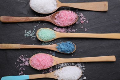 Photo of Spoons with different sea salts on black table, flat lay