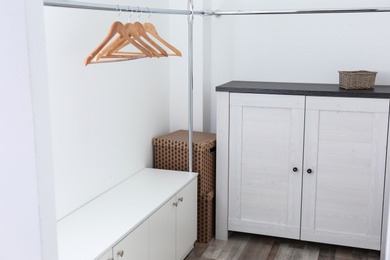 Modern dressing room interior with furniture and hangers