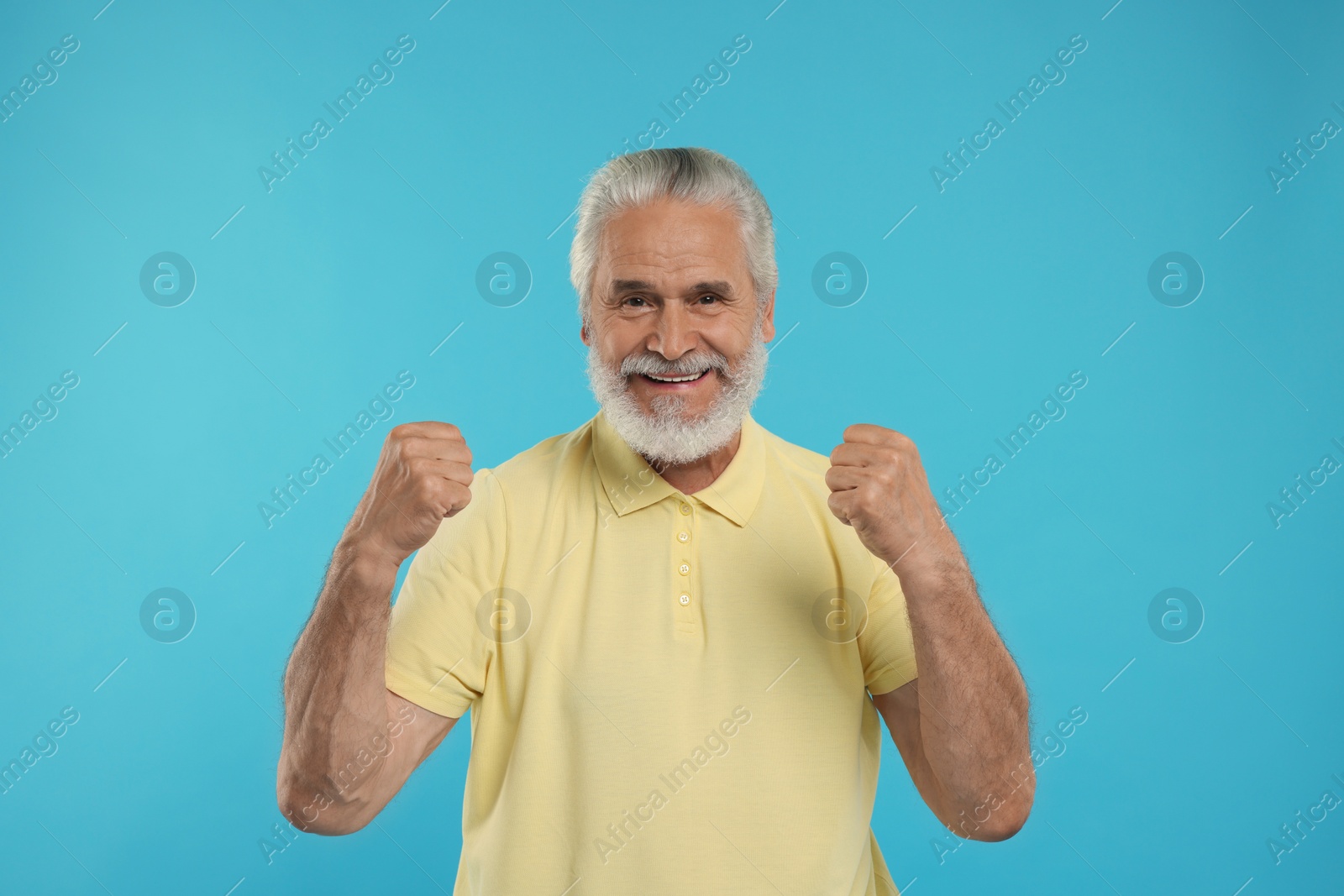 Photo of Happy senior sports fan on light blue background