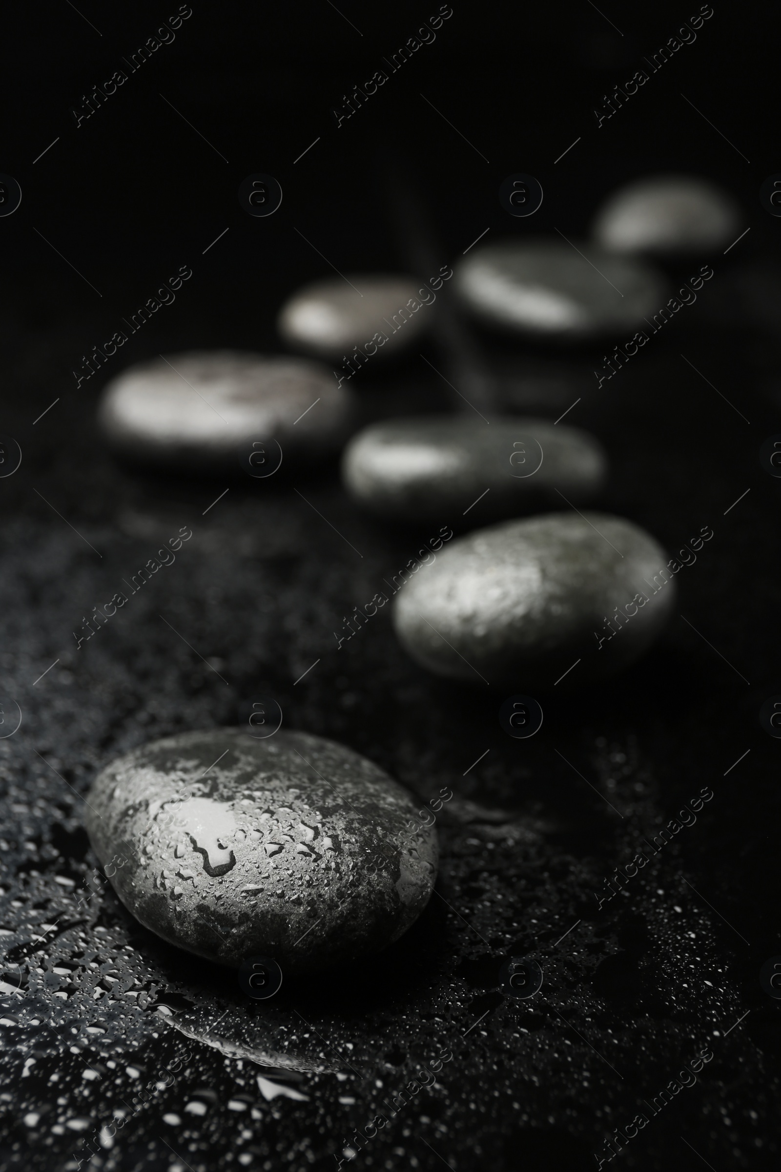 Photo of Wet spa stones on black background. Space for text