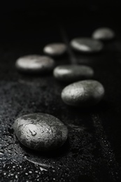 Wet spa stones on black background. Space for text