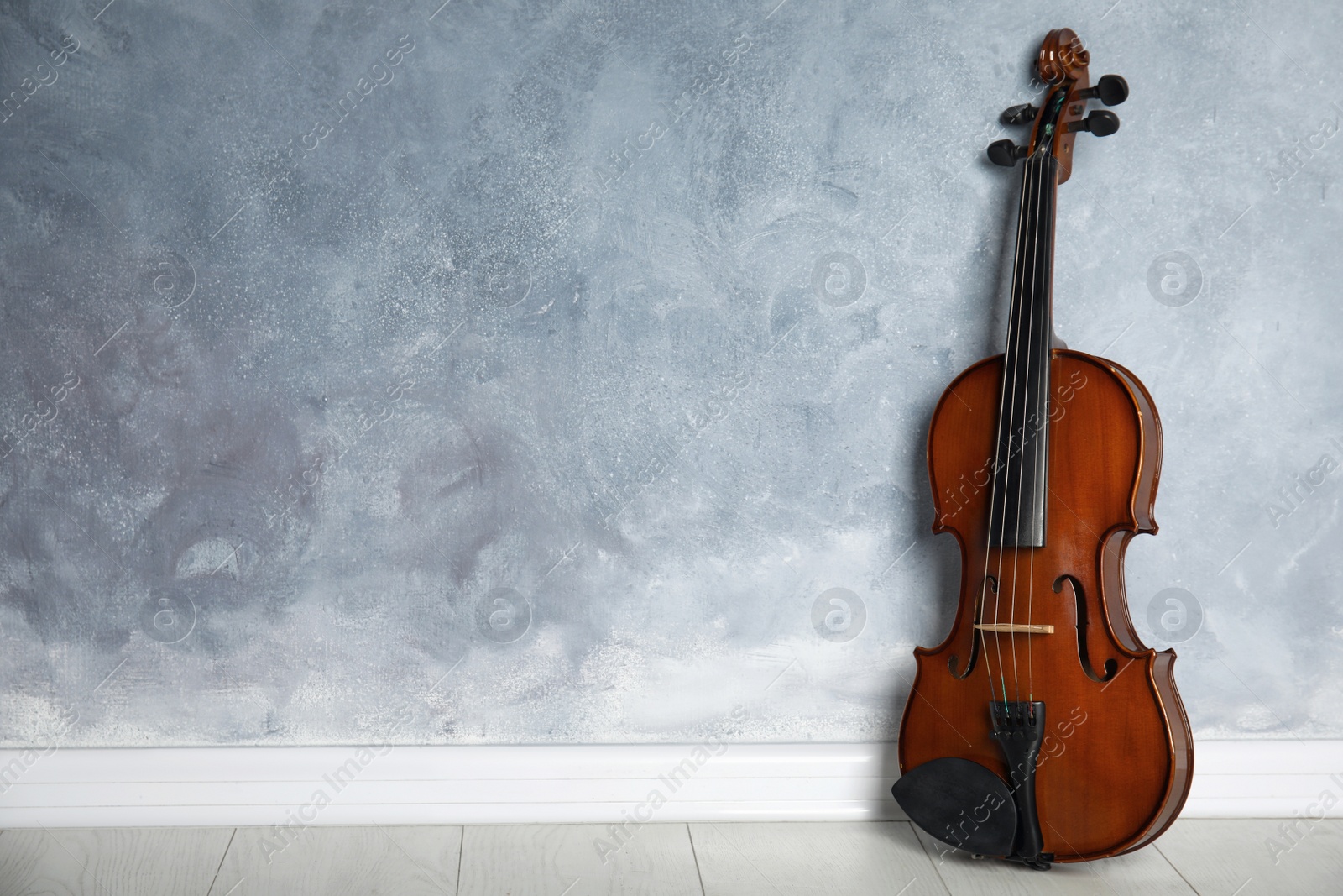 Photo of Classic violin on floor near grey wall. Space for text