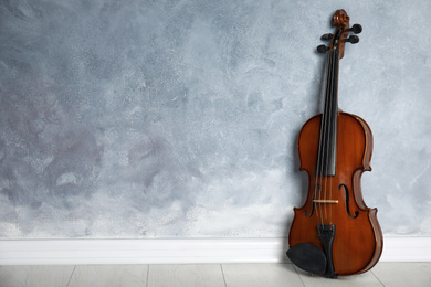 Classic violin on floor near grey wall. Space for text