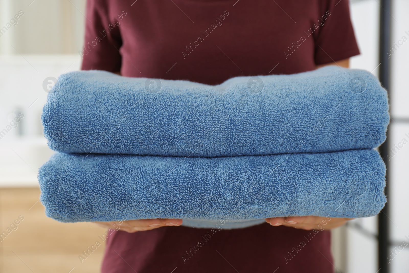 Photo of Woman holding fresh towels in bathroom, closeup