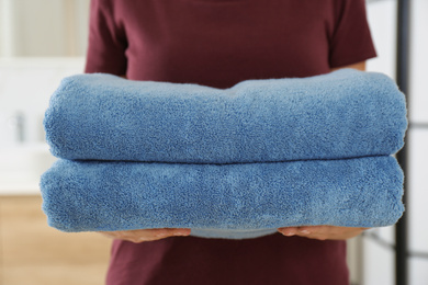 Woman holding fresh towels in bathroom, closeup