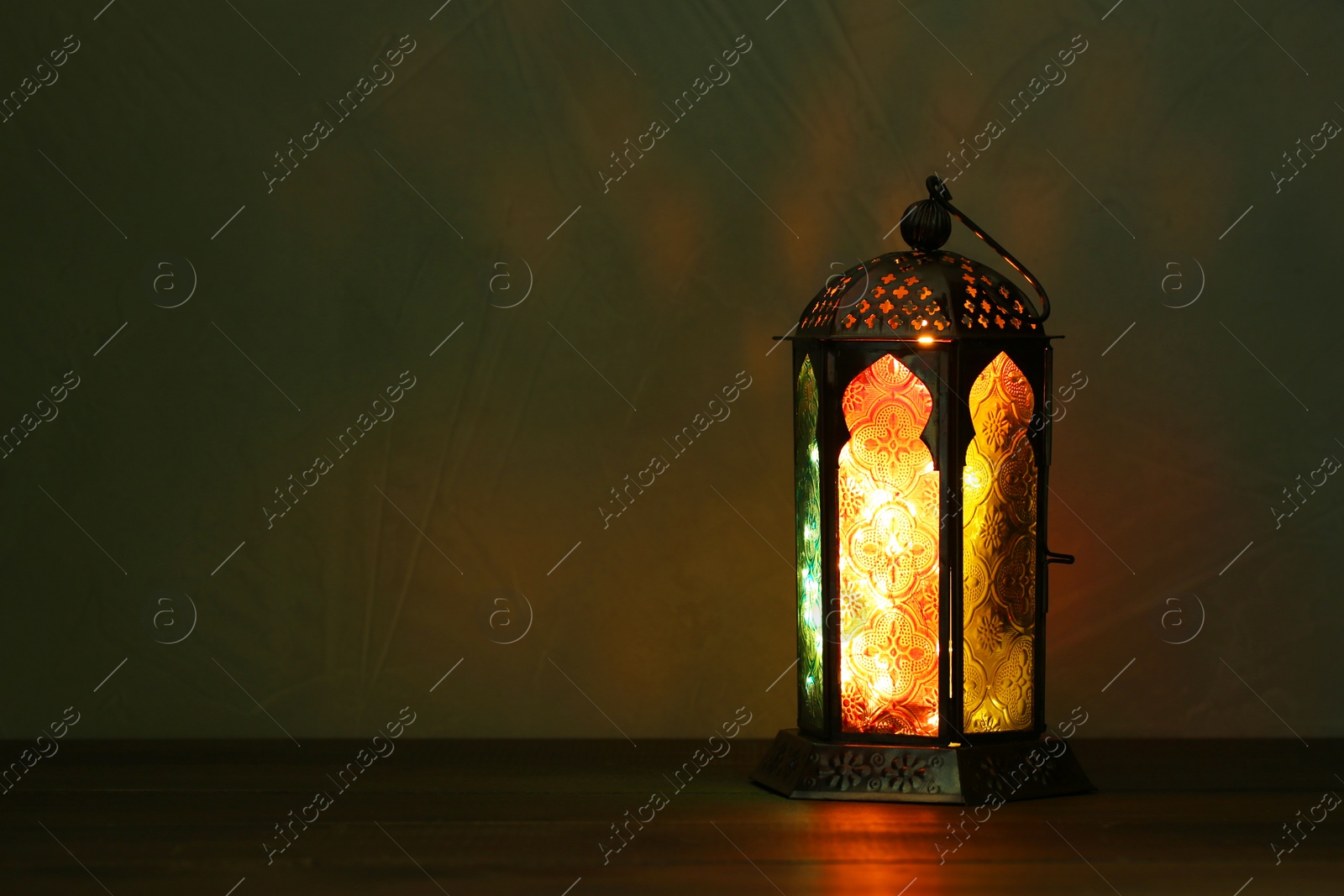 Photo of Decorative Arabic lantern on table against dark background. Space for text