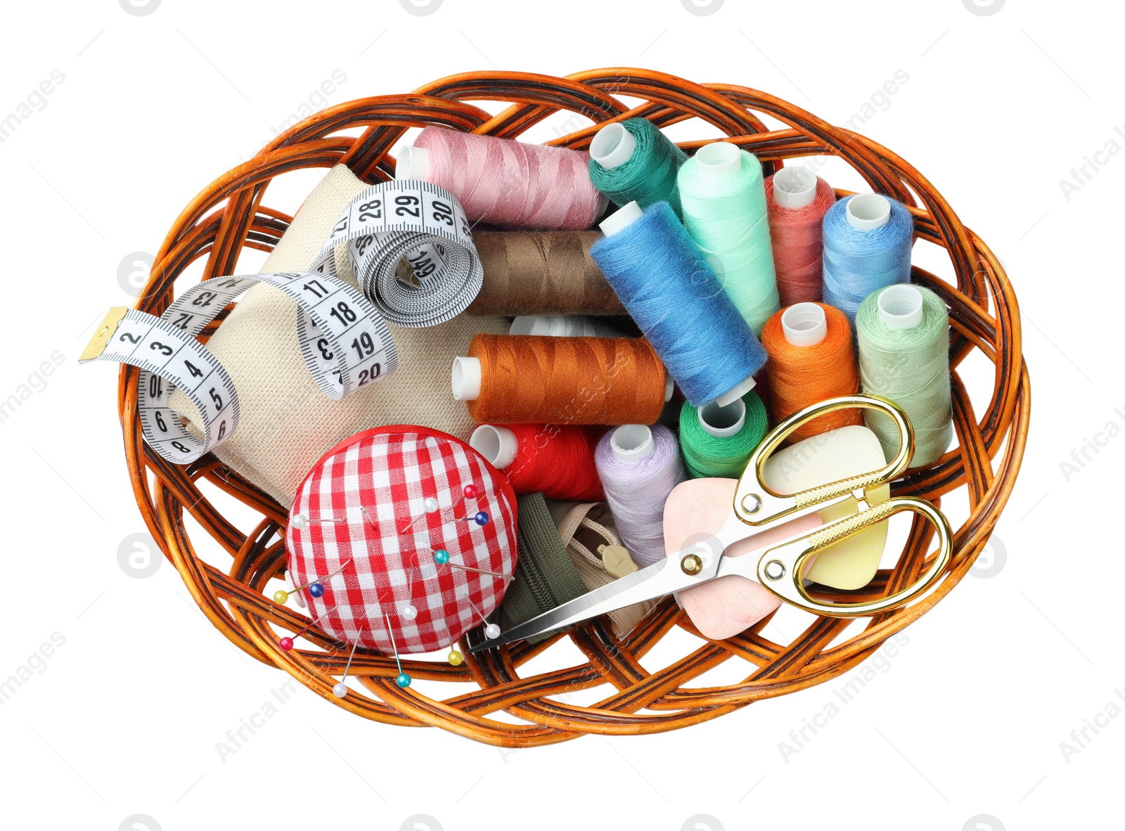 Photo of Wicker bowl with different sewing accessories on white background, top view