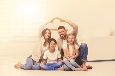 Image of Happy family forming house roof with their hands at home. Insurance concept