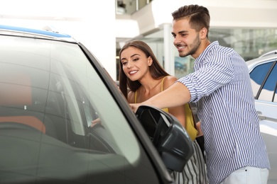 Young couple choosing new car in salon