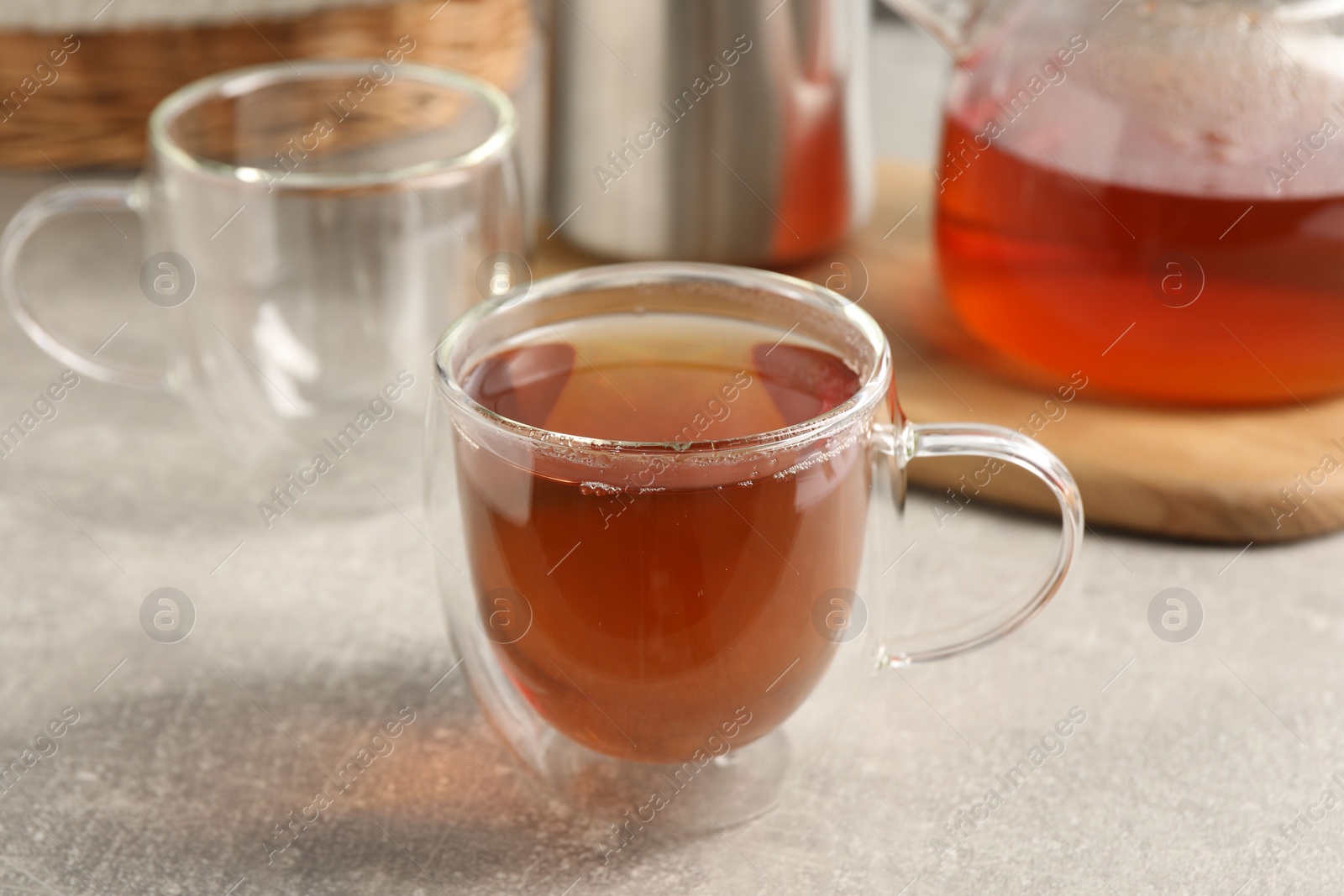 Photo of Aromatic tea in glass cup on light grey table