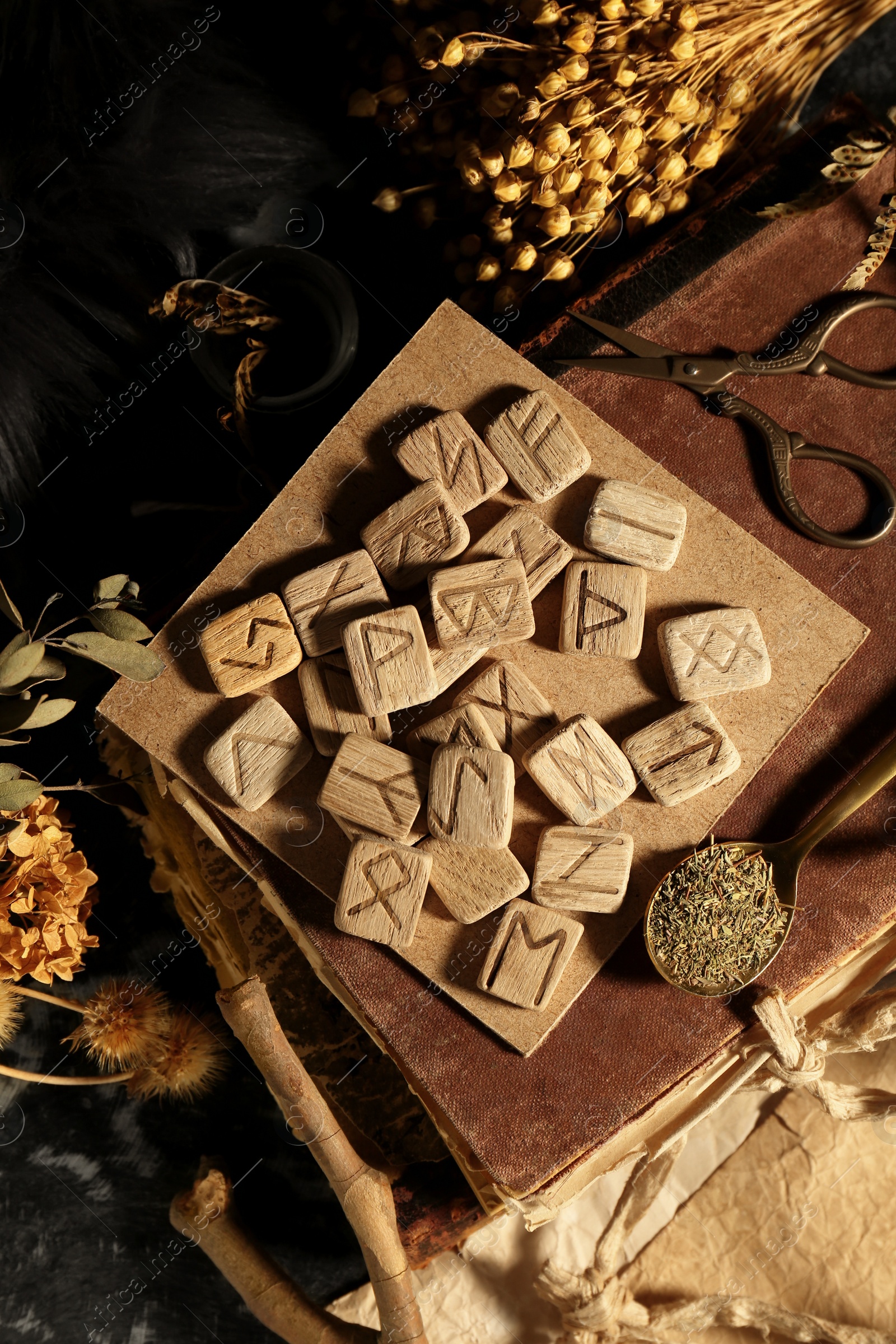 Photo of Many wooden runes, dried flowers and old books on altar, flat lay