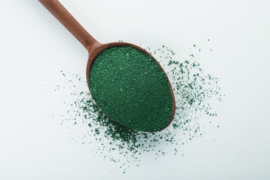 Photo of Spoon with spirulina algae powder on white background, top view