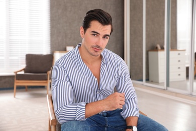 Portrait on handsome young man sitting in chair indoors