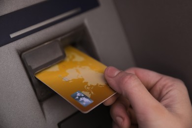 Photo of Woman inserting credit card into cash machine, closeup