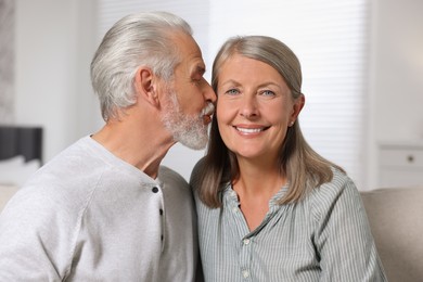 Photo of Senior man kissing his beloved woman indoors