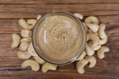 Tasty cashew nut paste in jar on wooden table, top view