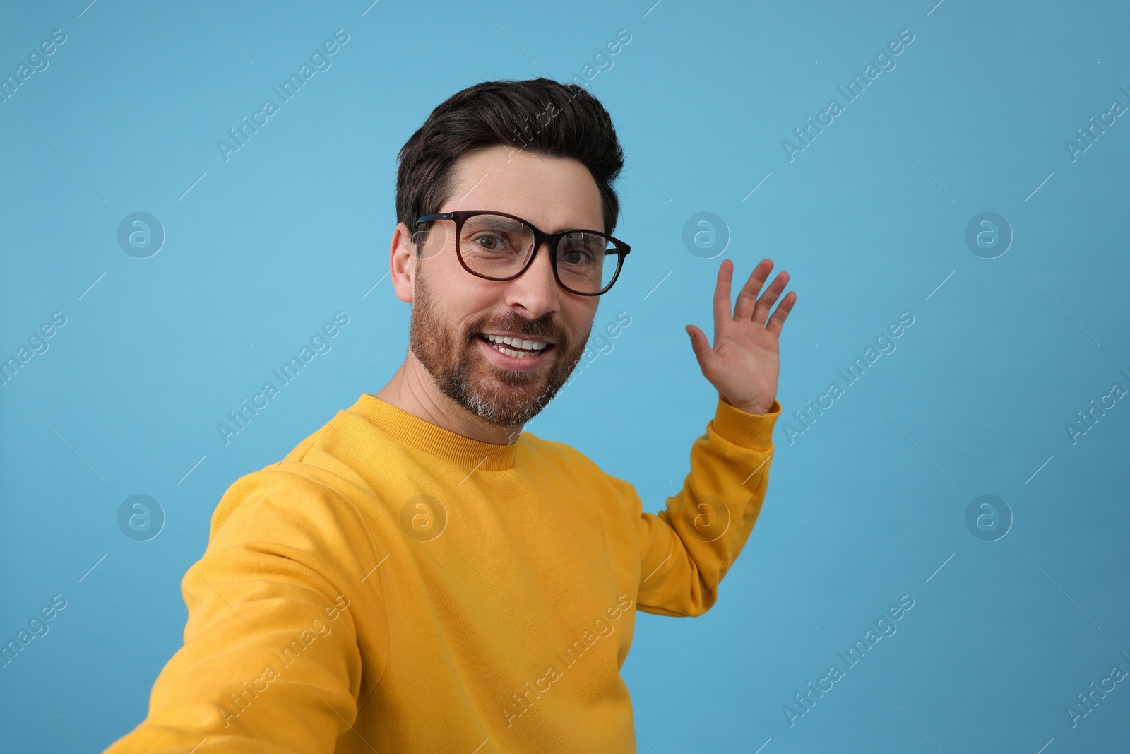 Photo of Smiling man taking selfie on light blue background