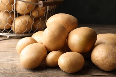 Raw fresh organic potatoes on wooden table, closeup