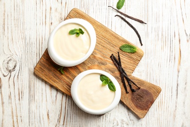 Photo of Vanilla pudding, sticks and fresh mint on wooden board