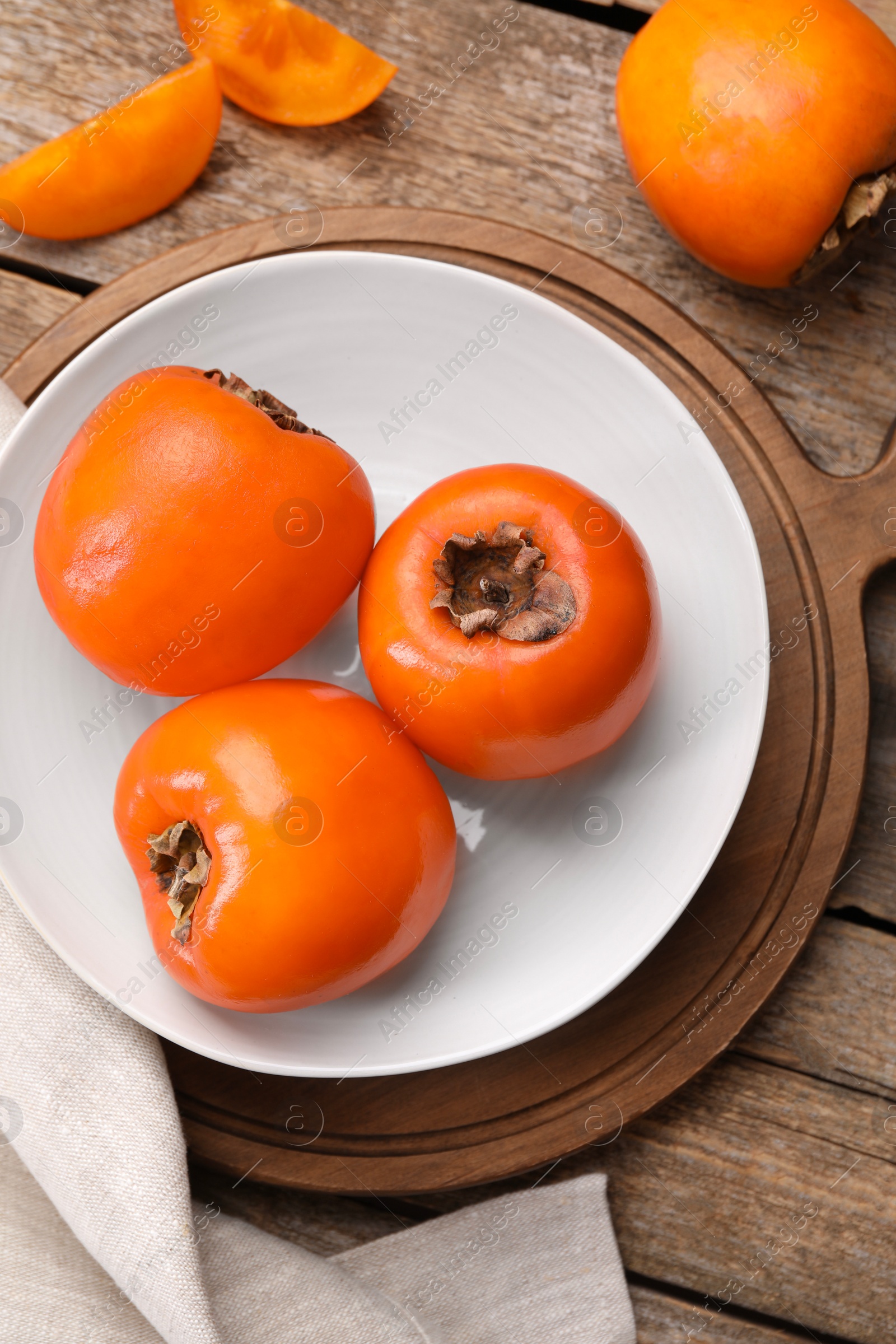 Photo of Delicious ripe persimmons on wooden table, top view