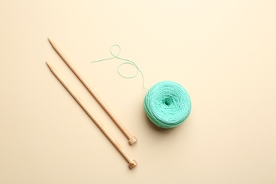 Photo of Clew of threads and knitting needles on color background, flat lay. Sewing stuff