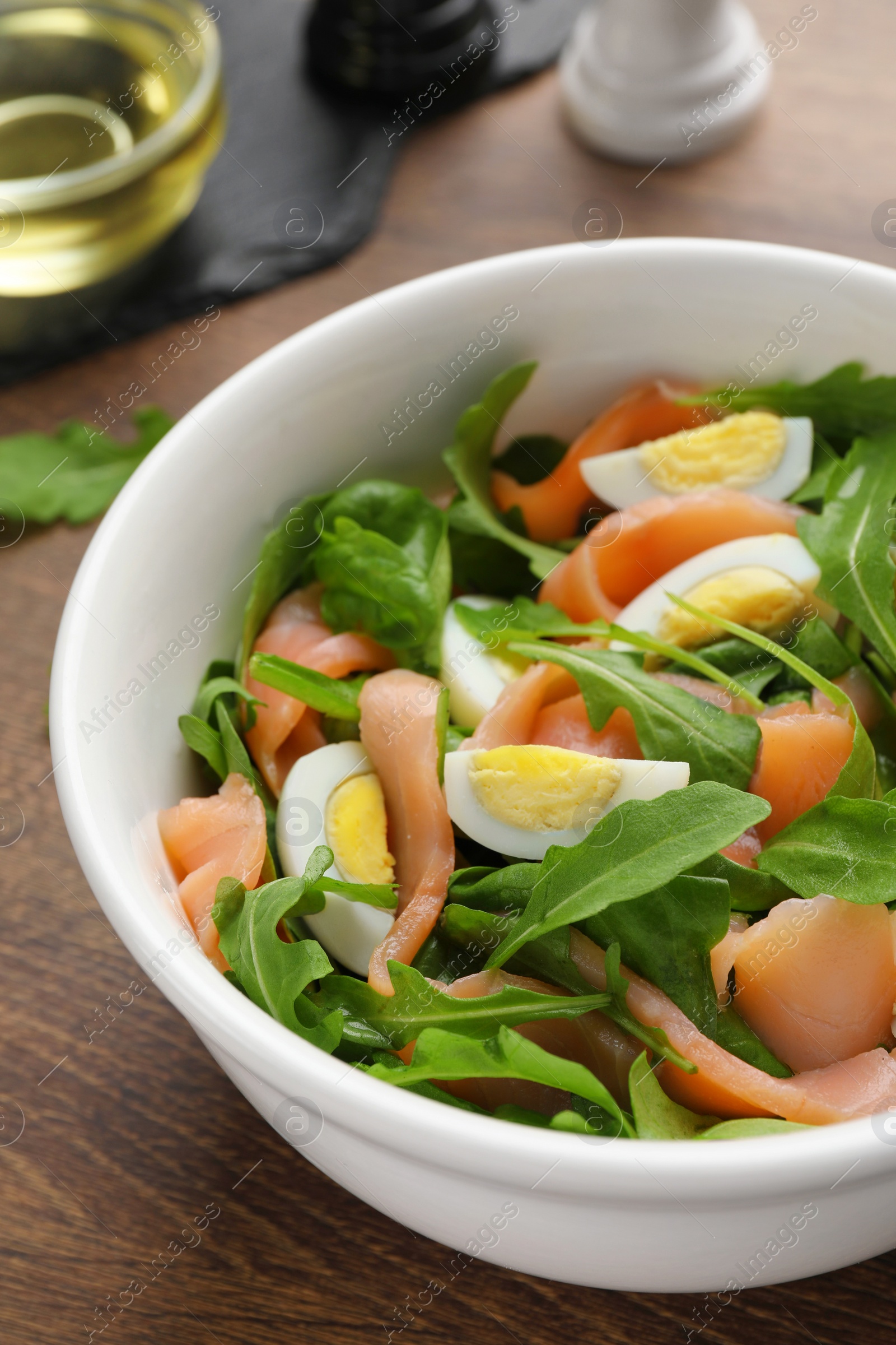 Photo of Delicious salad with boiled eggs, salmon and arugula on wooden table, closeup