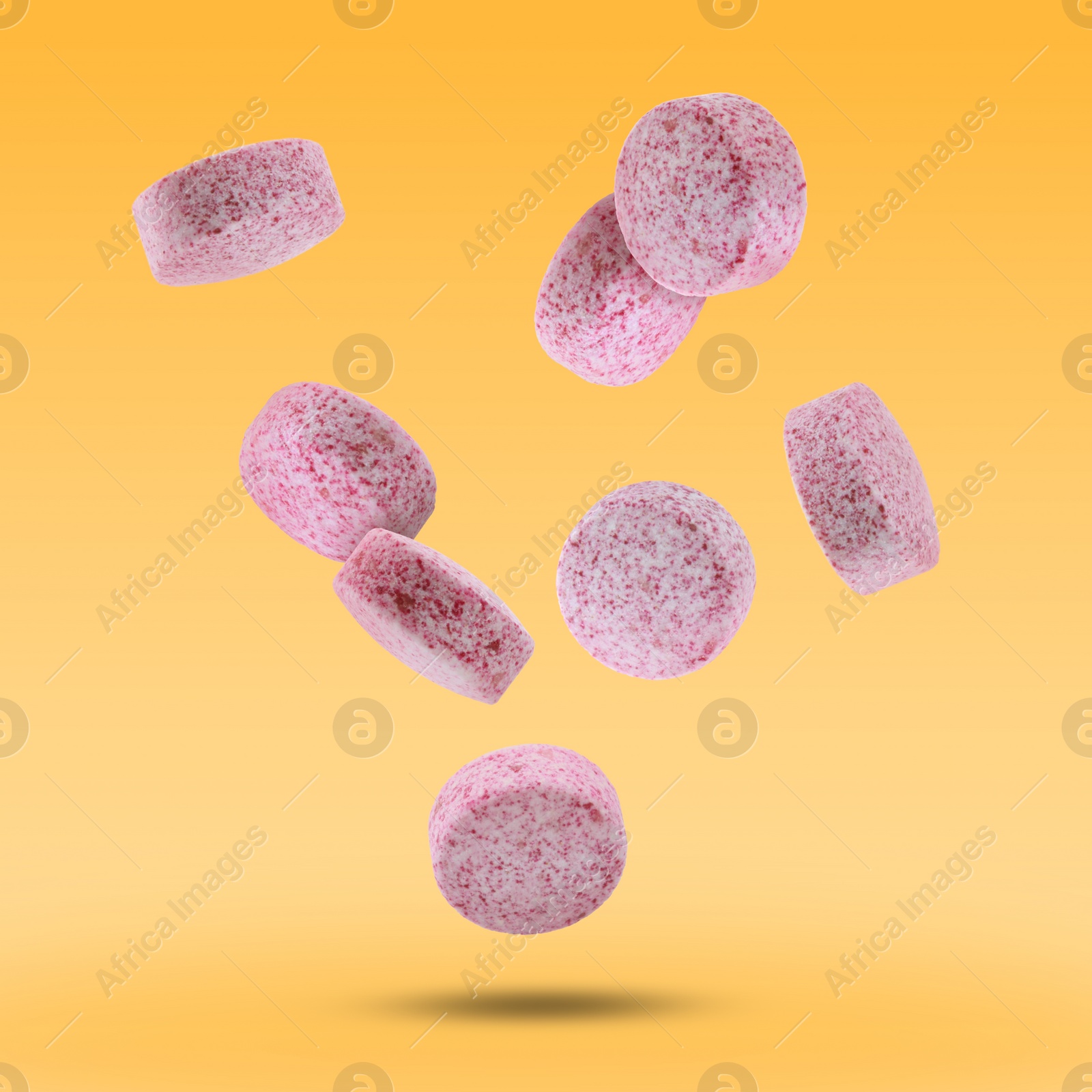 Image of Vitamin. Pink tablets falling on orange gradient background