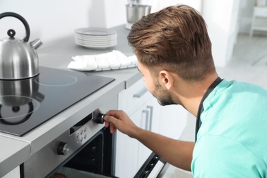 Young man baking something in oven at home