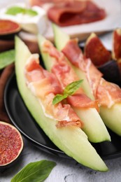 Photo of Tasty melon, jamon and figs served on white textured table, closeup
