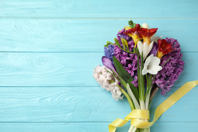 Photo of Bouquet of beautiful spring flowers on blue wooden table, top view. Space for text